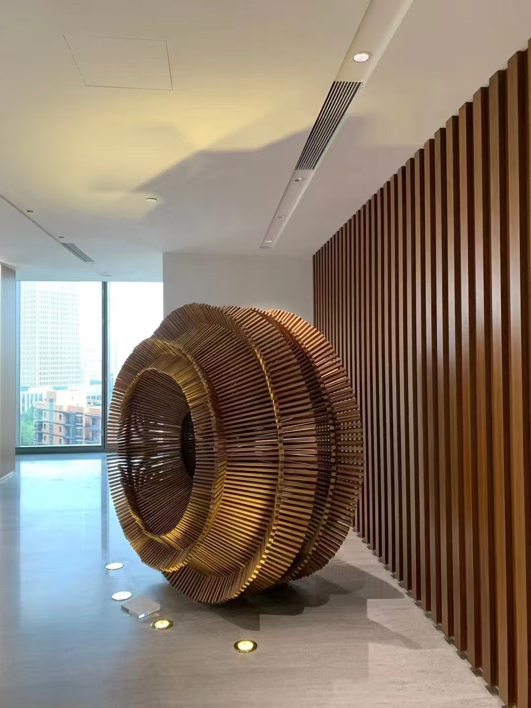 Installed bronze-tone stainless steel layered ring sculpture in a commercial interior