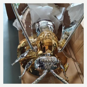 Chrome and gold winged insect sculpture viewed from the side