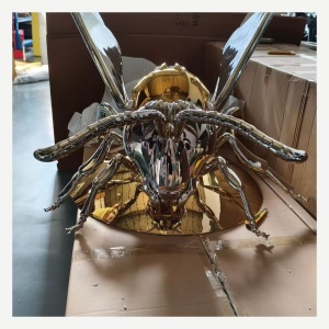 Front view of the same reflective winged insect sculpture
