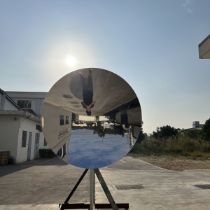 Concave mirror stainless steel disc sculpture during final outdoor reflection inspection