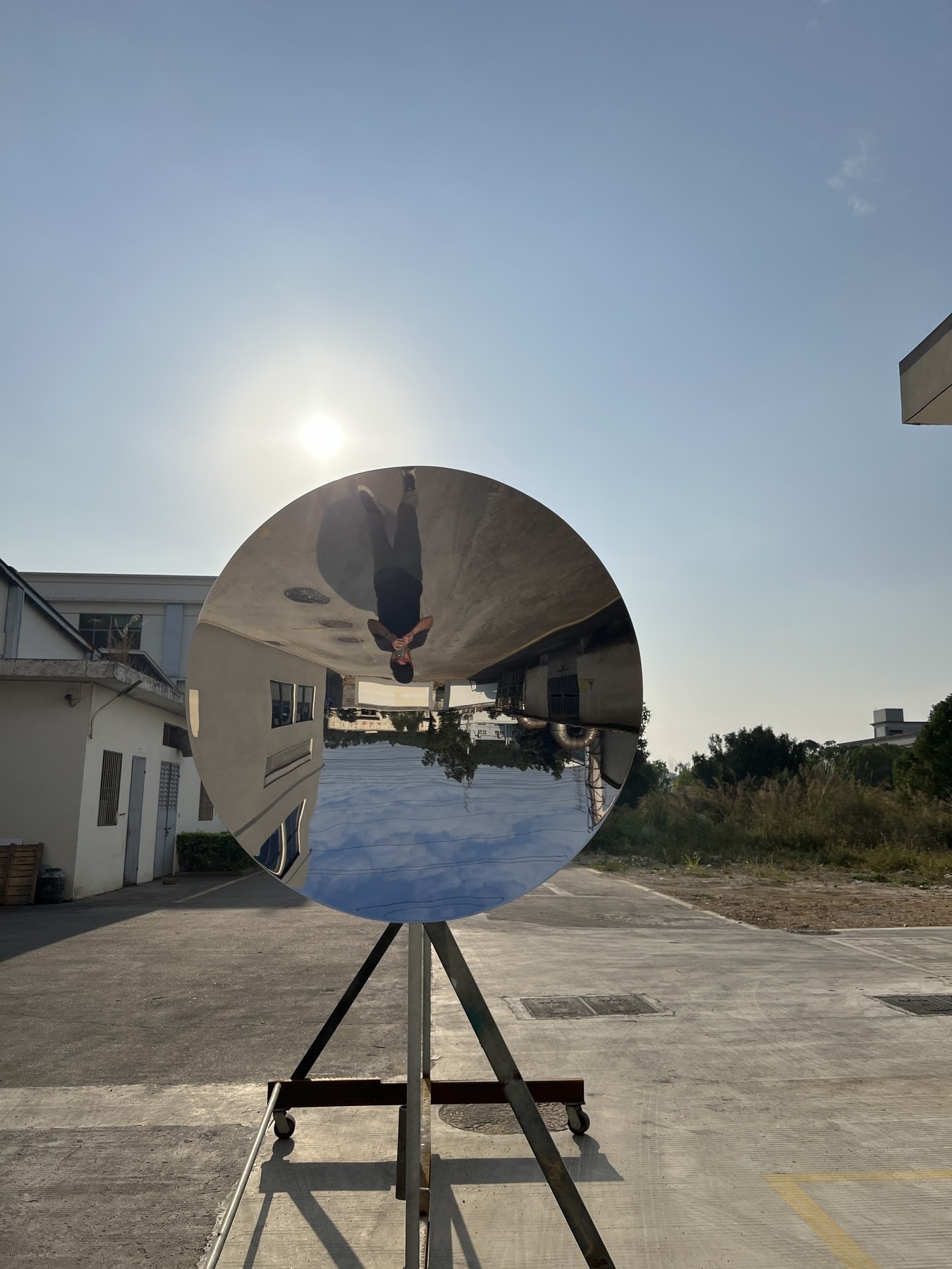 Concave mirror stainless steel disc sculpture during final outdoor reflection inspection
