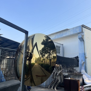 Golden mirror disc sculpture viewed from another angle