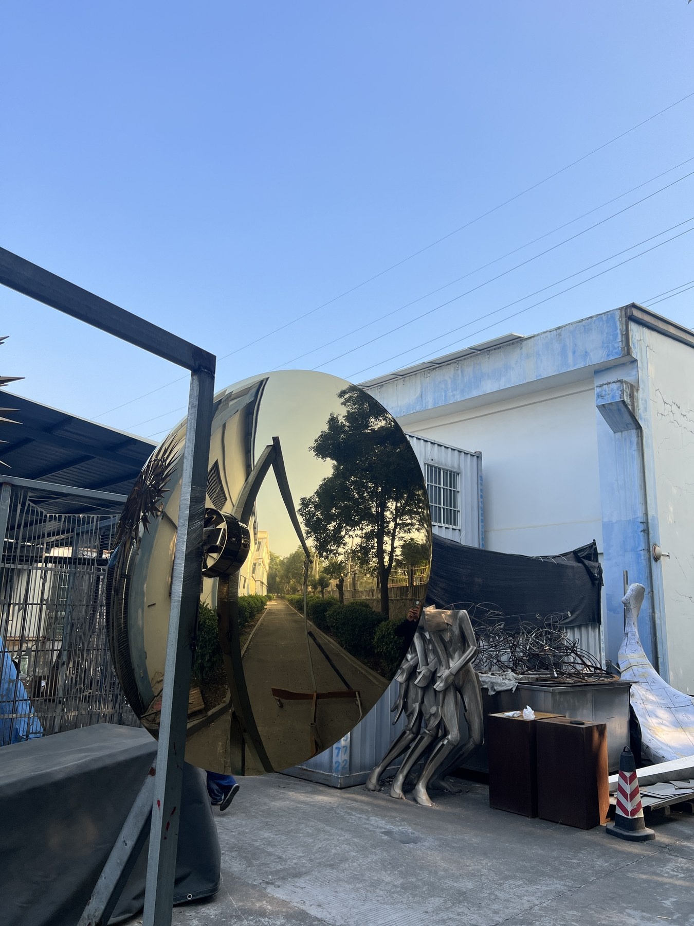 Golden mirror disc sculpture viewed from another angle