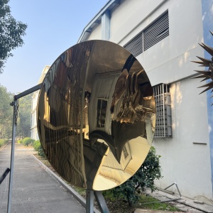 Side view of the same golden mirror stainless steel disc sculpture