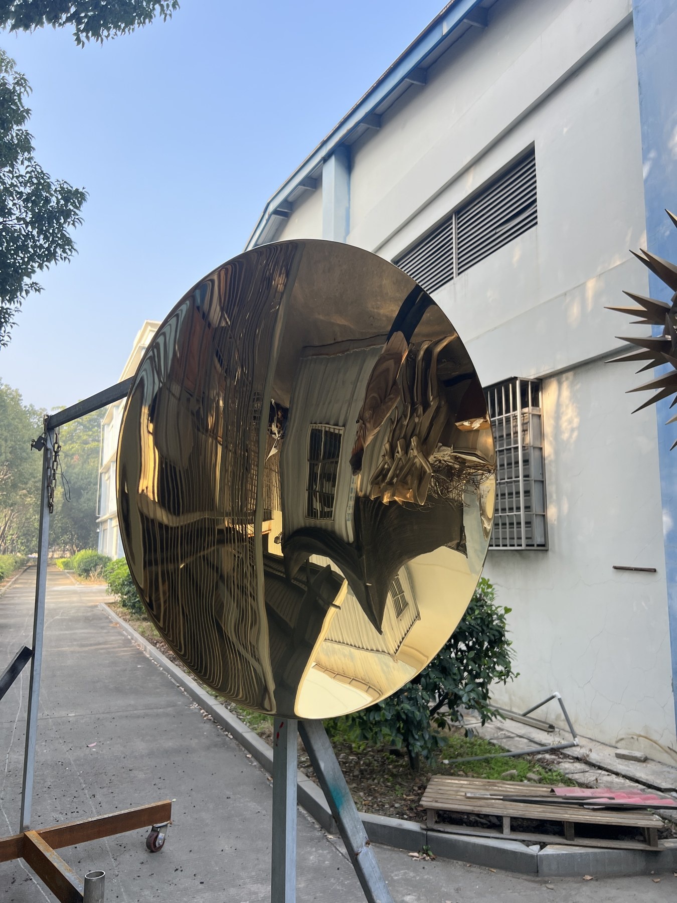 Side view of the same golden mirror stainless steel disc sculpture