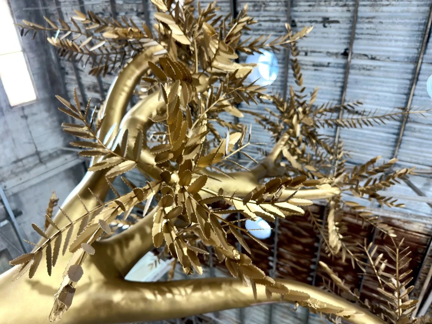 Golden stainless steel leaf and branch detail on the same tree sculpture
