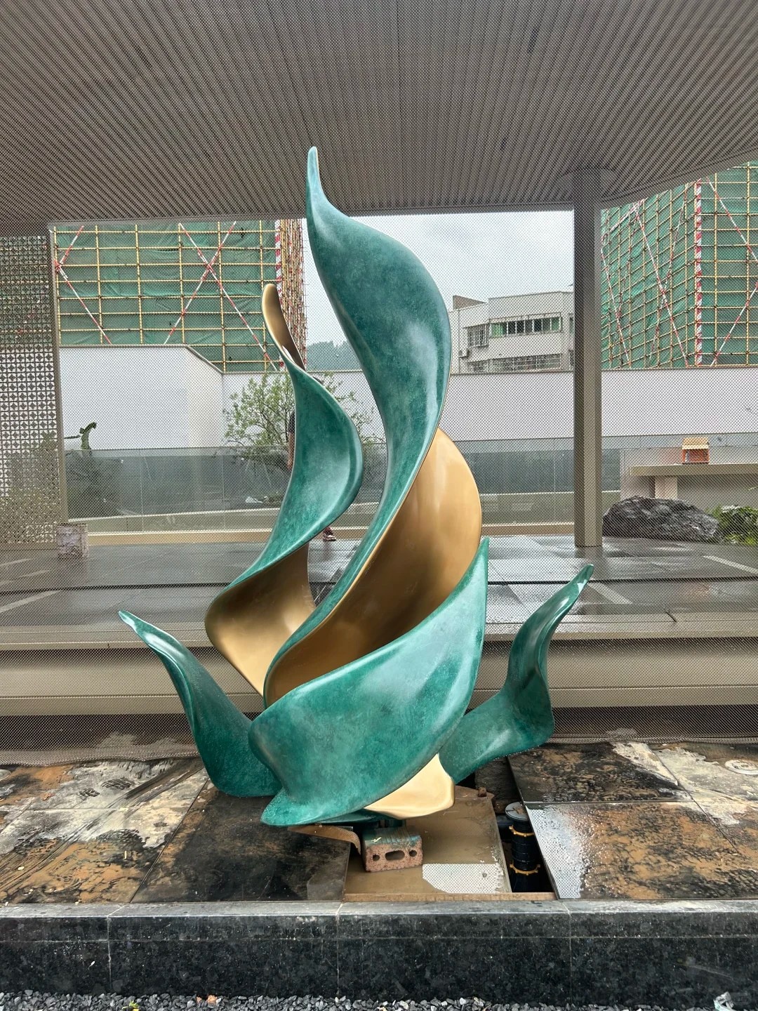 Completed green patina stainless steel leaf sculpture in a landscape installation setting