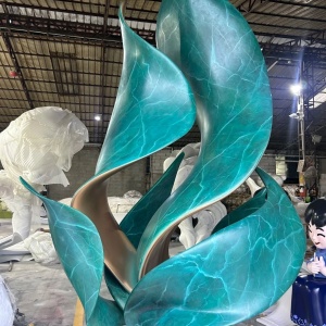Three-quarter workshop view of the same stainless steel leaf sculpture