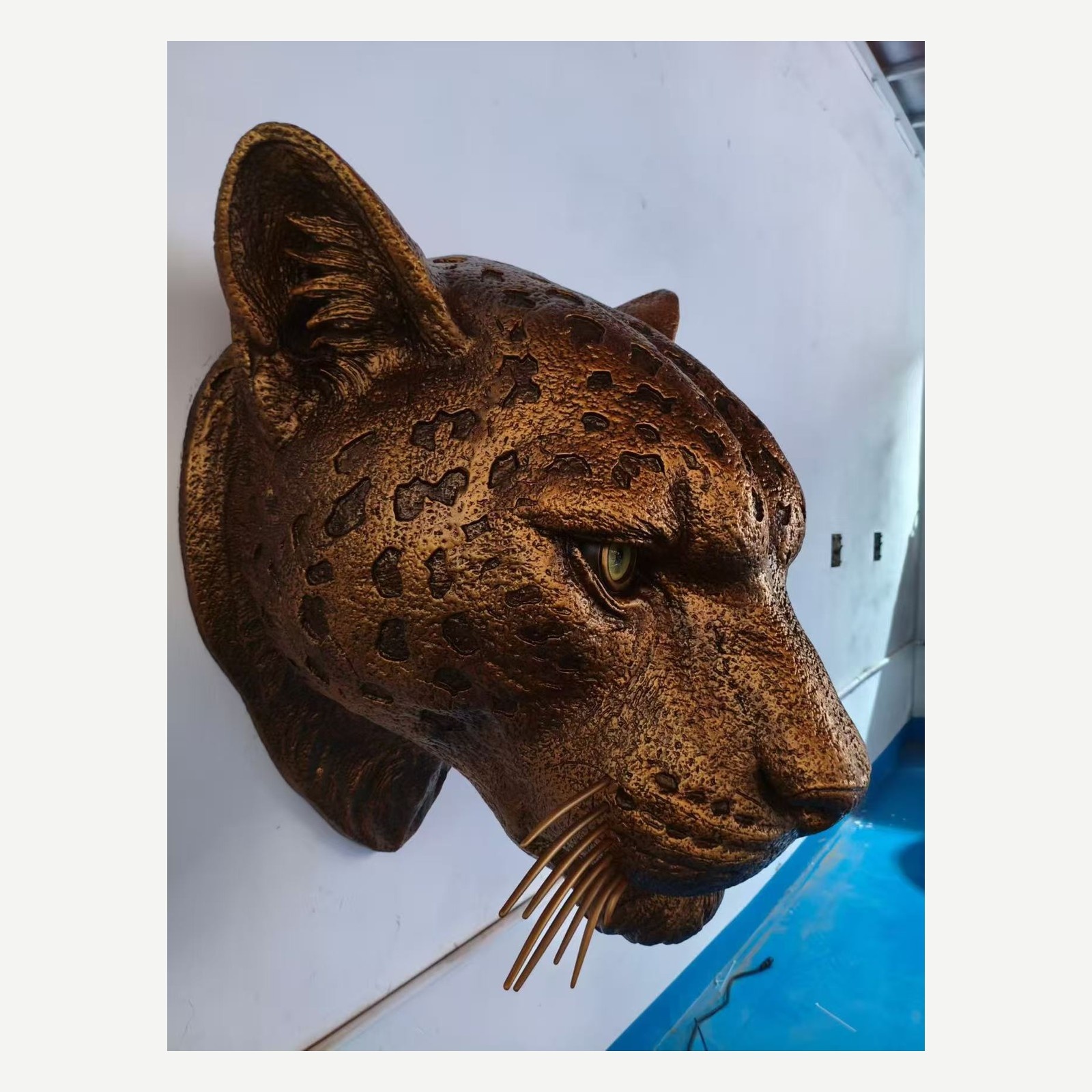 Side view of the same leopard head wall-mounted sculpture