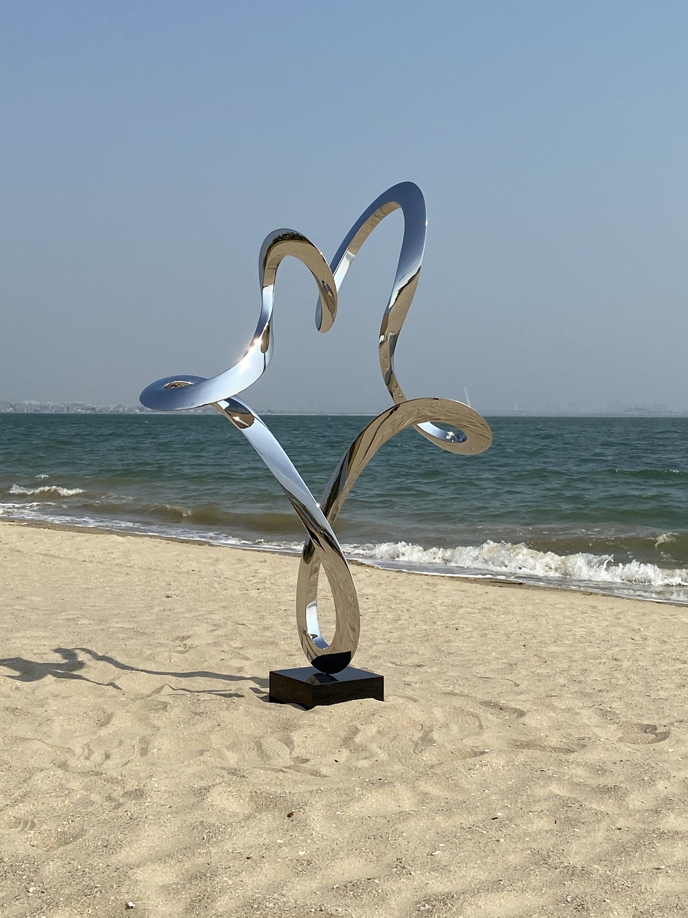 Second finished angle of the same mirror stainless steel abstract figure sculpture