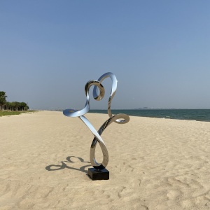 Full coastal view of the same mirror stainless steel abstract figure sculpture