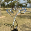 Mirror stainless steel branching ribbon sculpture in a park landscape