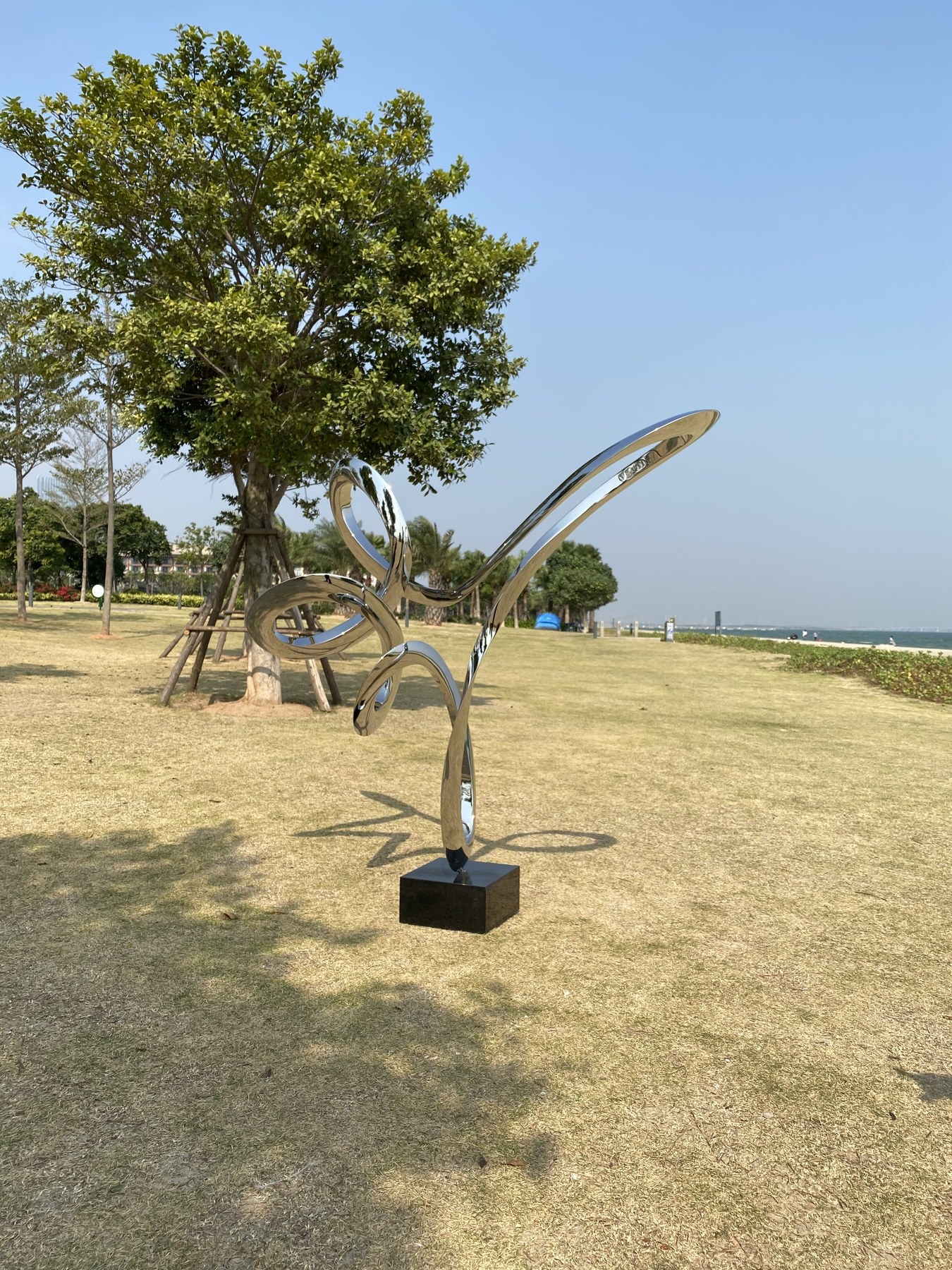 Installed mirror stainless steel loop sculpture in an outdoor landscape