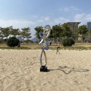 Installed mirror stainless steel ribbon sculpture in a coastal landscape