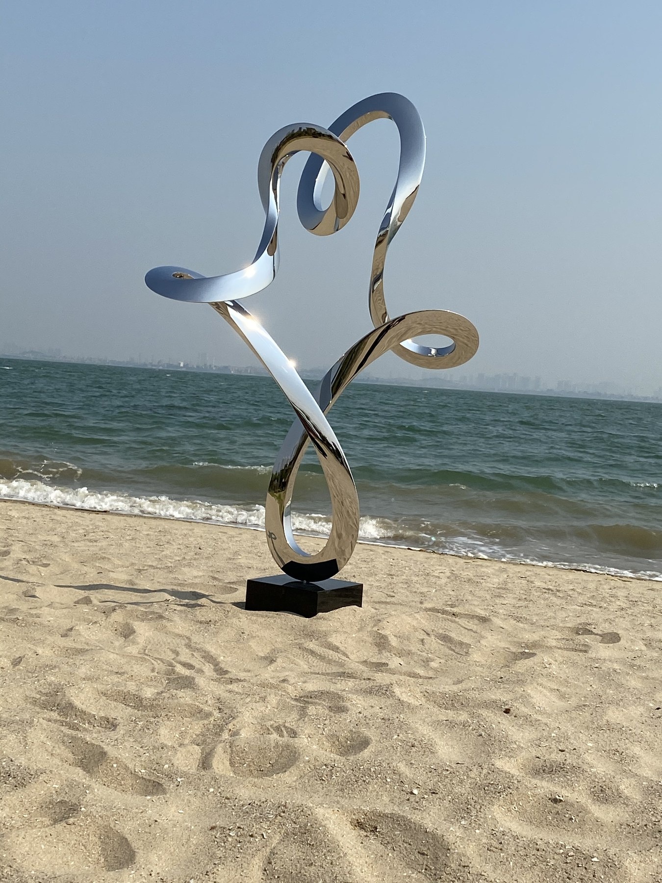 Outdoor project context for the same mirror ribbon sculpture