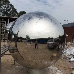 Finished mirror stainless steel sphere sculpture viewed outdoors
