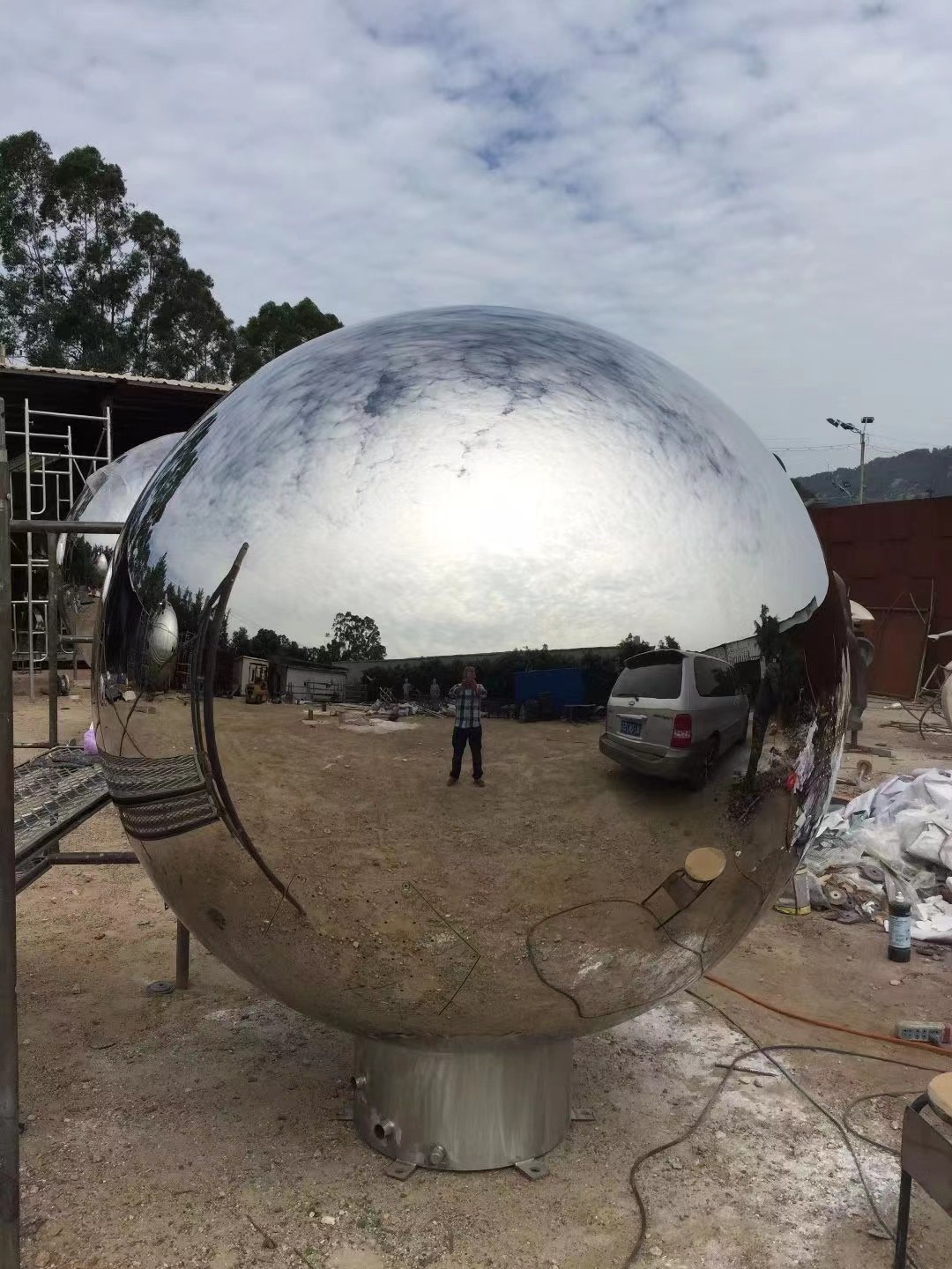 Finished mirror stainless steel sphere sculpture viewed outdoors