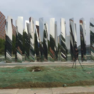 Mirror stainless steel vertical blade sculpture assembled in an outdoor staging area