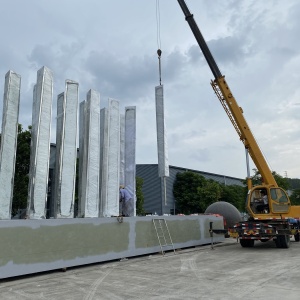 Crane assembly of the same large mirror stainless steel vertical blade sculpture