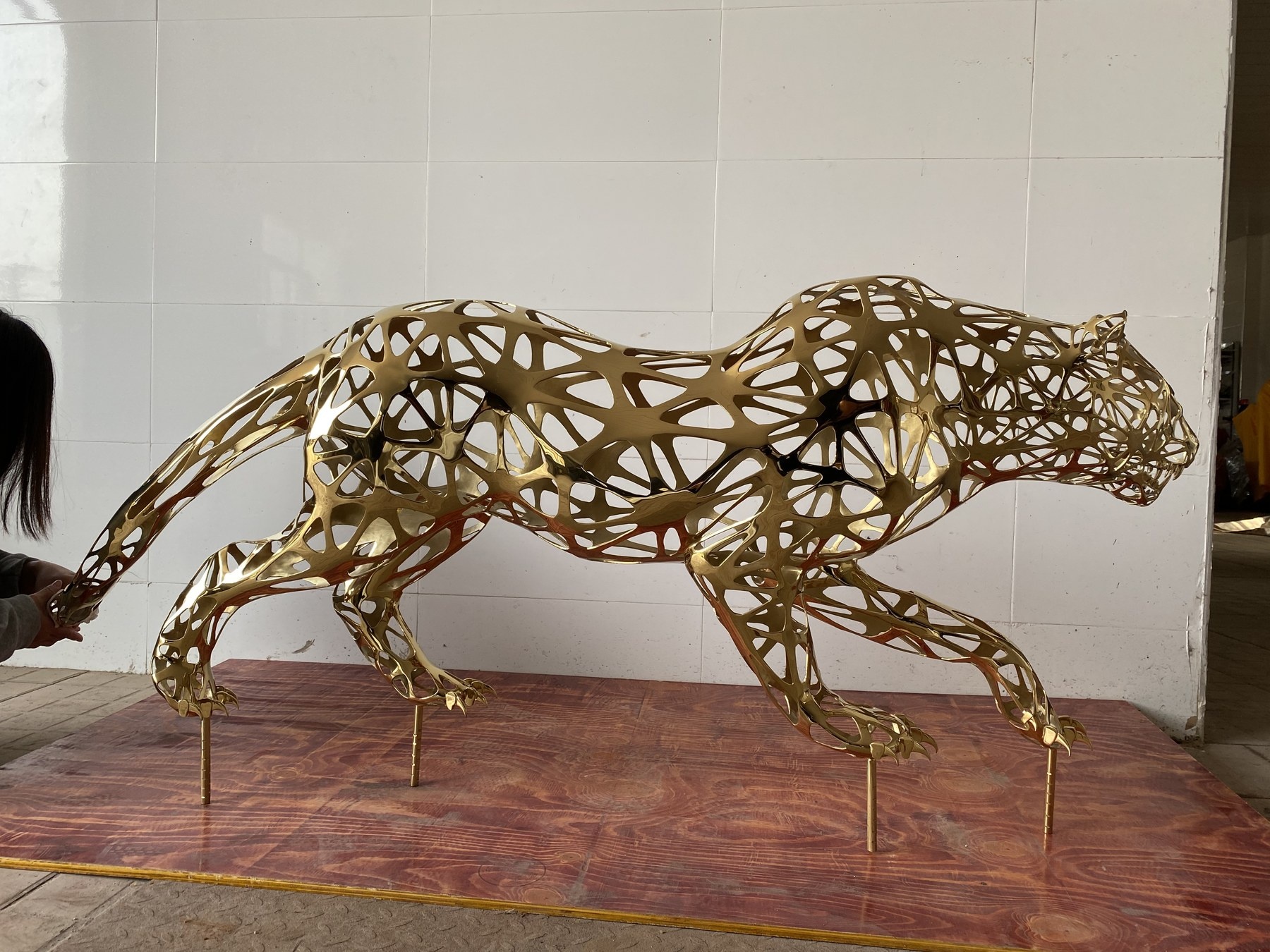 Side view of the same gold stainless steel leopard sculpture
