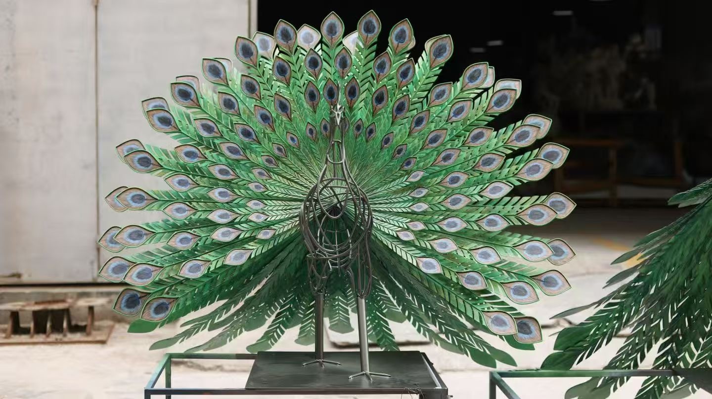 Painted metal peacock sculpture with open tail during workshop completion review