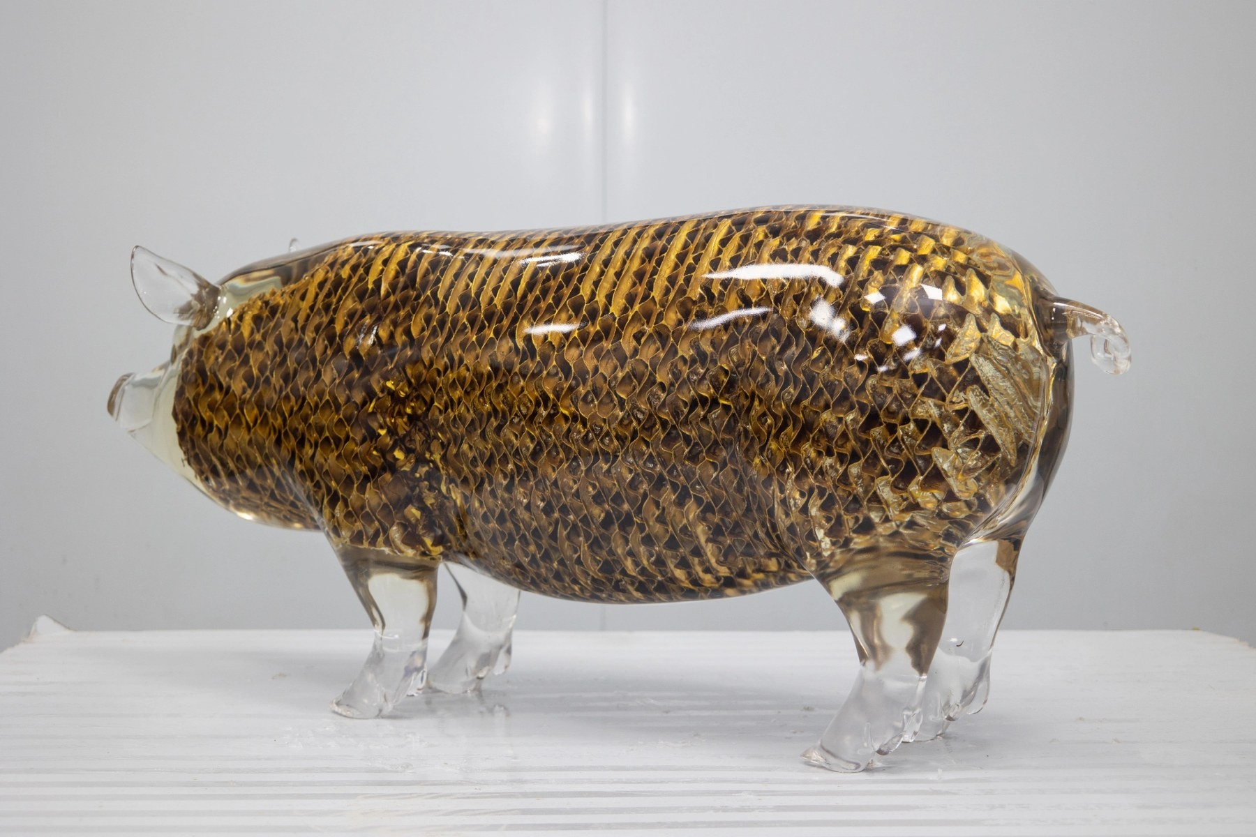 Openwork surface and transparent golden finish detail on the same pig sculpture