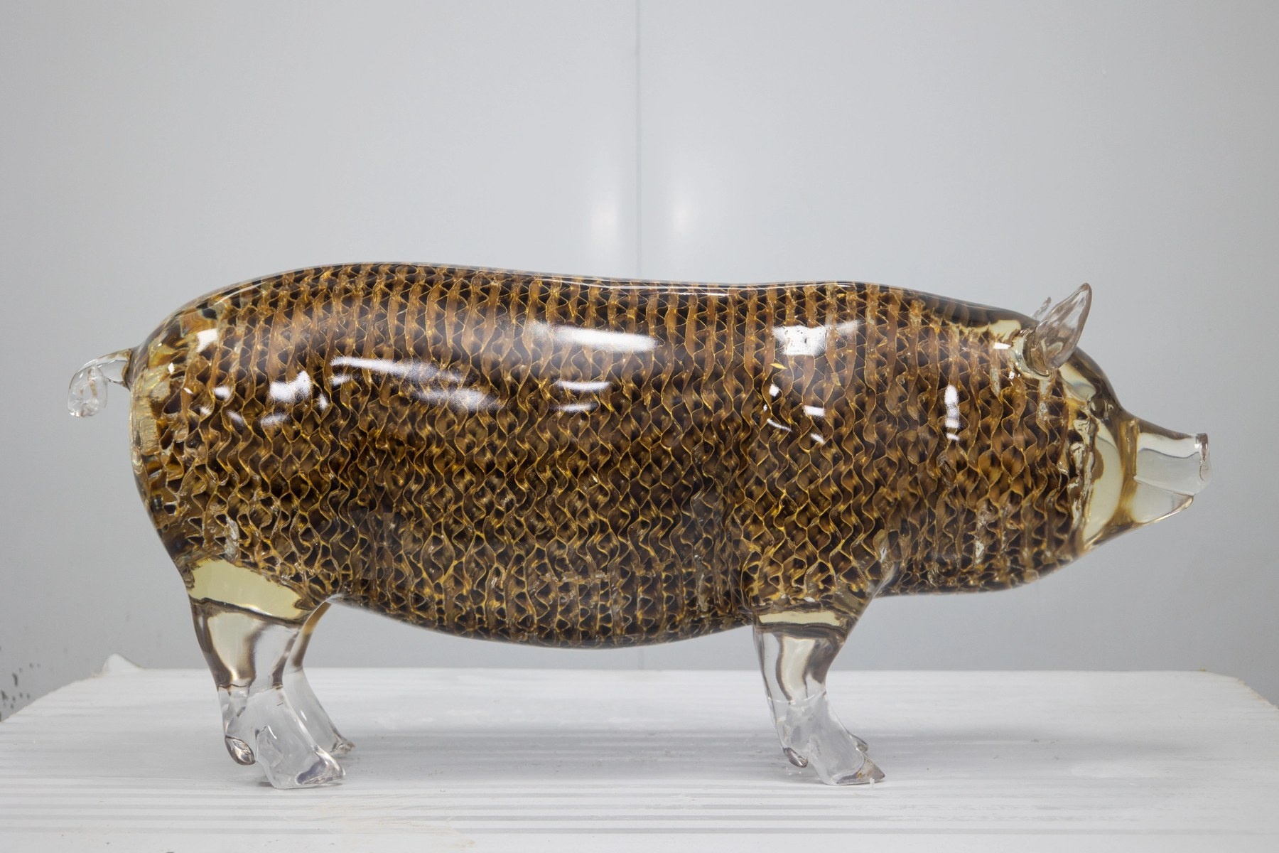 Rear three-quarter view of the same transparent pig display sculpture